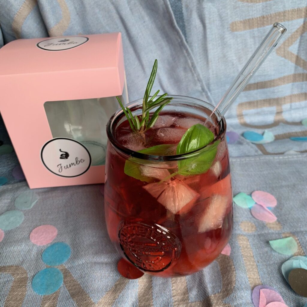 ReJumbo Trinkglas mit rotem Sommerdrink, Eis, Basilikum und Glasstrohhalm