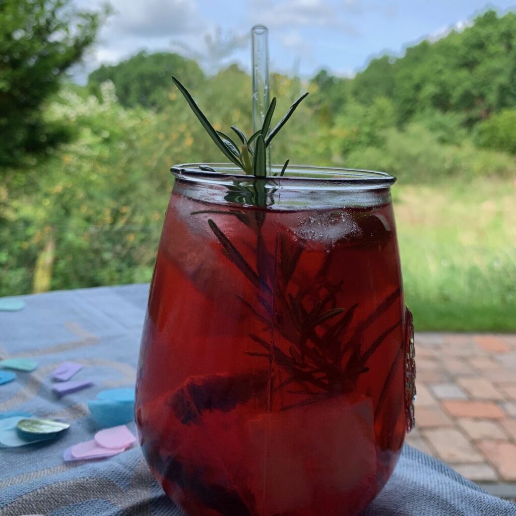 ReJumbo Glas mit rotem Drink vor grünem Gartenhintergrund
